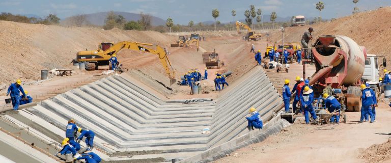 Trabalhadores e betoneira em canal de concreto em construção