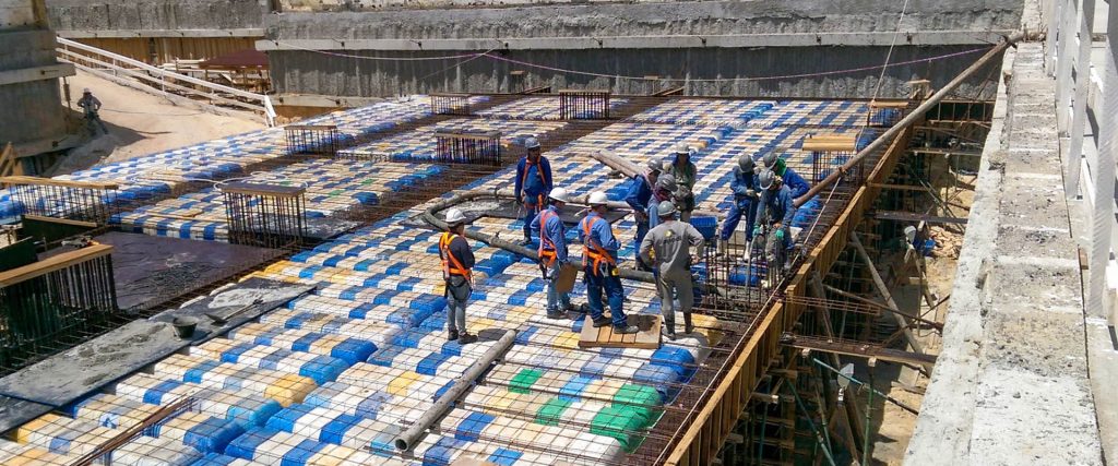 Trabalhadores sobre laje com fôrmas plásticas em obra
