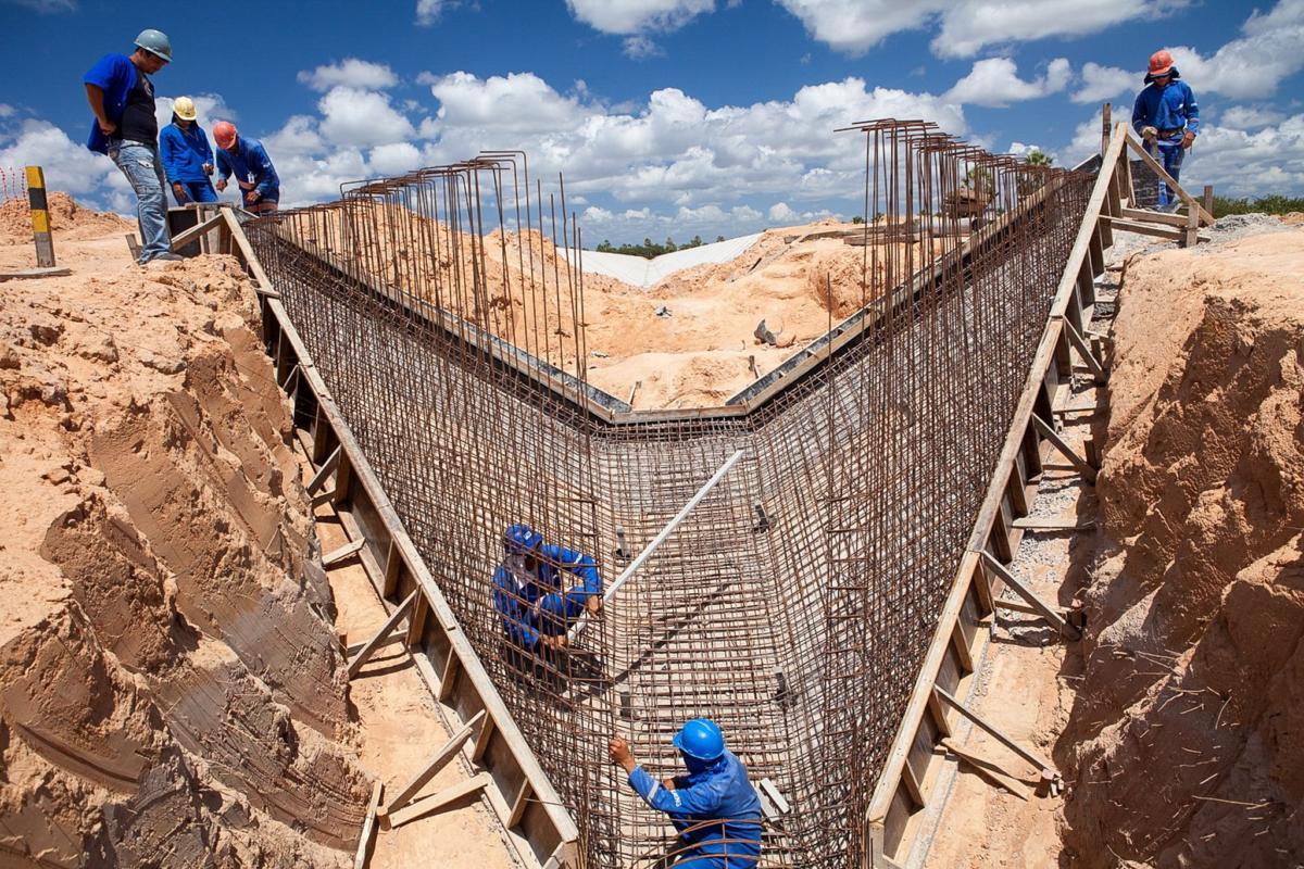 Trabalhadores na armação de aço de um canal de concreto