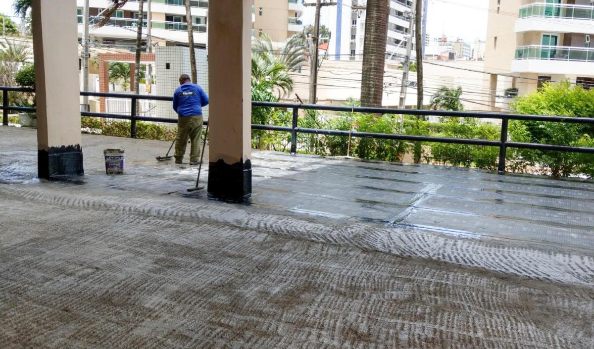 Trabalhador aplicando impermeabilização em laje de cobertura